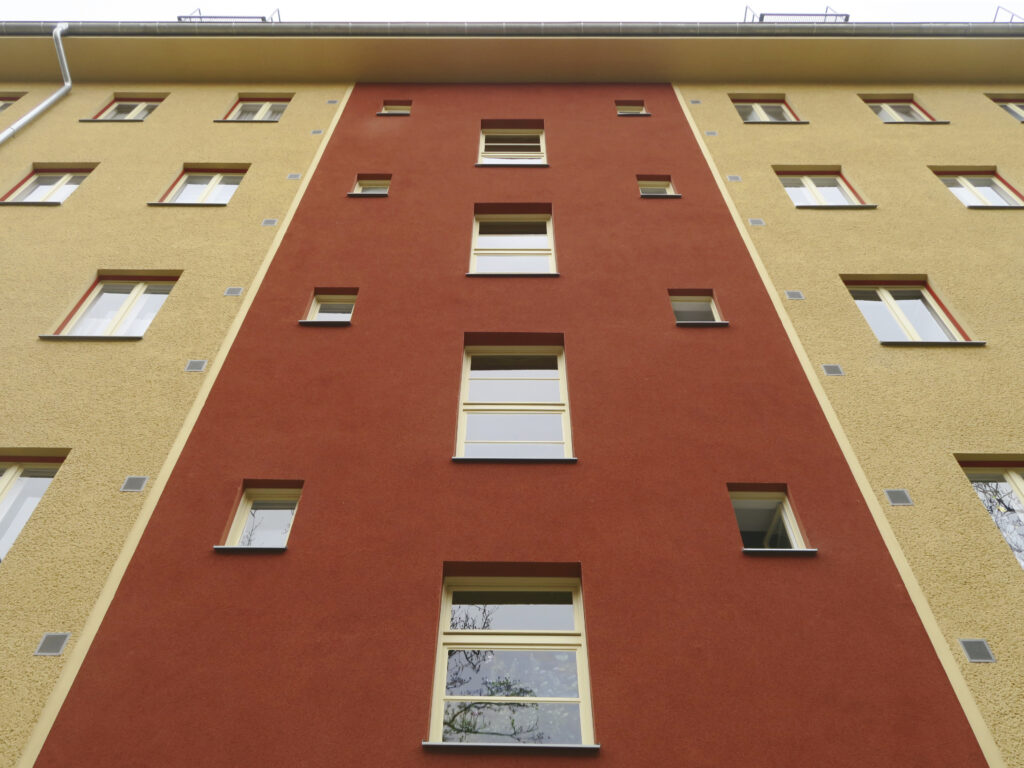 Nahaufnahme der Putzfassade, die im Bereich des Treppenhauses haushoch mit rotem Putz akzentuiert wurde.