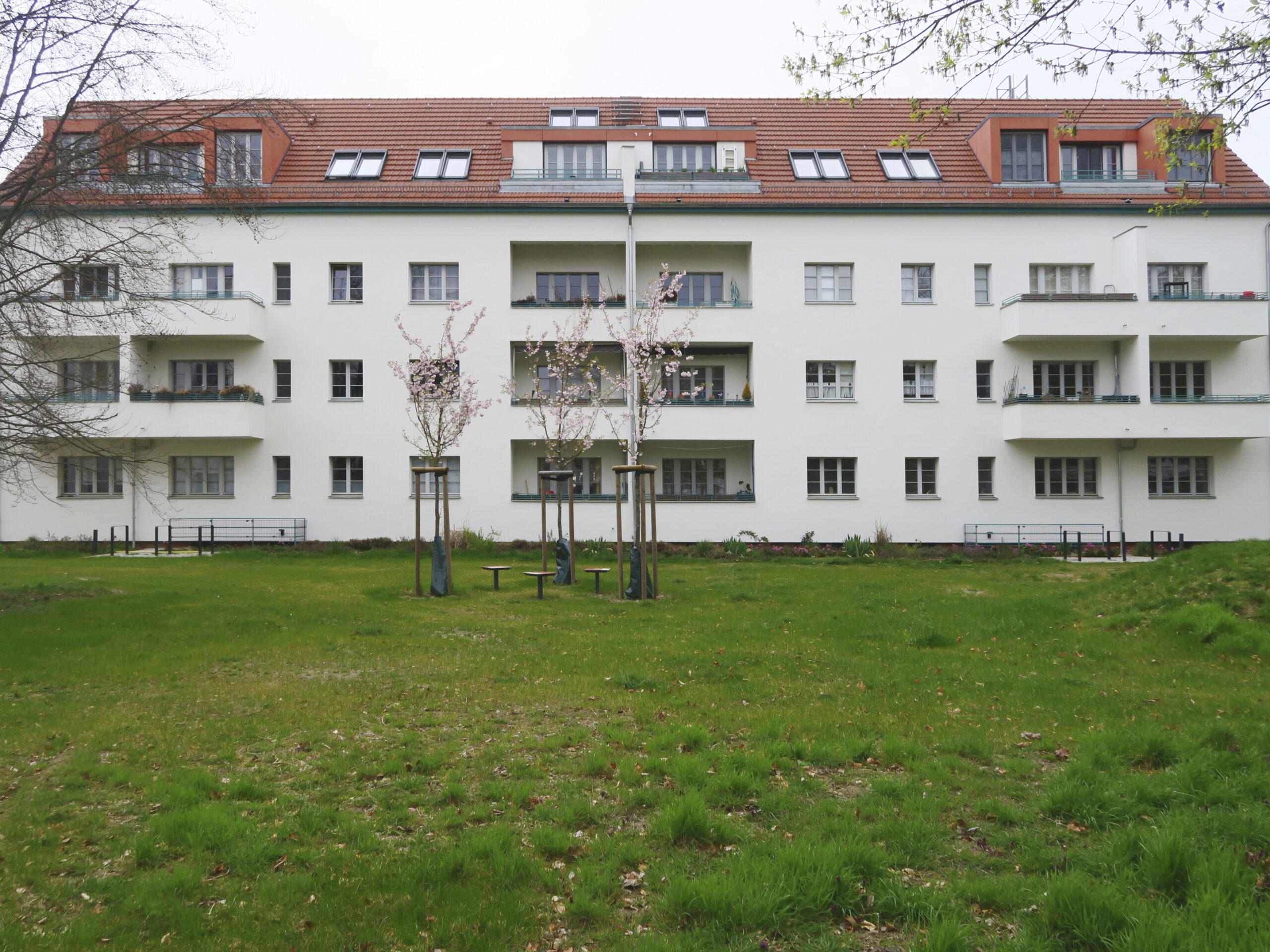 Blick auf die neu gestaltete Fassade eines dreigeschossigen Wohnhauses mit neu gebauten Dachgauben und Dachterrassen.
