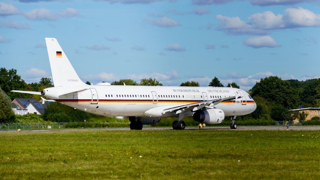 Ein weißes Flugzeug der Bundesregierung Deutschland mit schwarz-rot-goldenen Streifen an den Seiten rollt auf einem Flugfeld zur Startbahn.