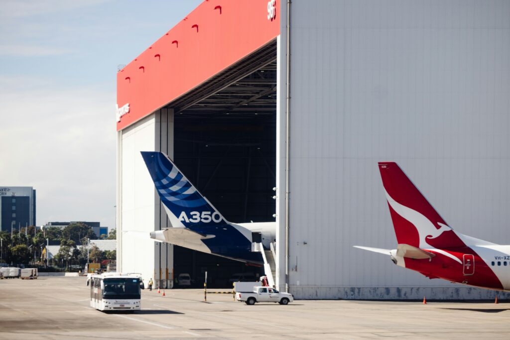 Aus einem riesigen Flugzeughangar schaut das Heck eines Airbus A350.
